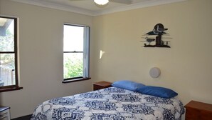 A bedroom with a bed, a window, a wall-mounted artwork, and a nightstand. - Dunbar Court Unit 8 - South West Rocks (SOUTH WEST ROCKS)