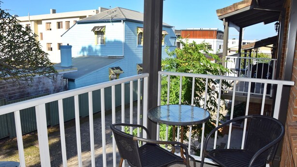 A balcony with two wicker chairs and a small round table. - Dunbar Court Unit 8 - South West Rocks (SOUTH WEST ROCKS)