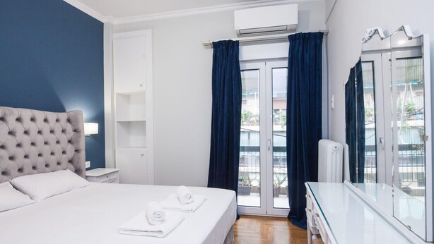 A hotel room with a bed, a dresser, a window with curtains, and an air conditioning unit.