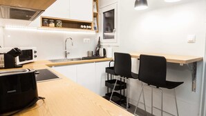 A compact kitchen with a microwave, sink, and two black chairs.