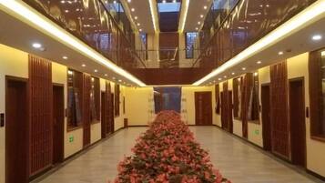 Un pasillo de hotel con un arreglo floral central, puertas de madera y un diseño moderno de techo.