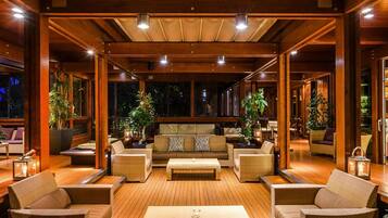 A spacious indoor area with wooden flooring, a central sofa, and multiple wicker chairs.