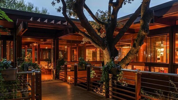 A wooden deck with a covered area, surrounded by plants and a large tree. - Resort Riva degli Etruschi, San Vincenzo (San Vincenzo)