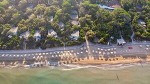 An aerial view of a coastal area with several buildings, some with traditional roofs, and a beach with a road running parallel to the shore. - Resort Riva degli Etruschi, San Vincenzo (San Vincenzo)