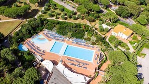 An aerial view of a resort with a large pool area, multiple lounge chairs, and a well-maintained garden. - Resort Riva degli Etruschi, San Vincenzo (San Vincenzo)