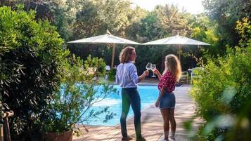 Zwei Personen stehen an einem Pool mit Sonnenschirmen.