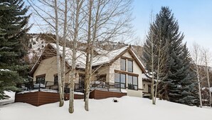 Een groot, twee verdiepingen tellend huis met een sneeuwbedekte dak en een houten terras.