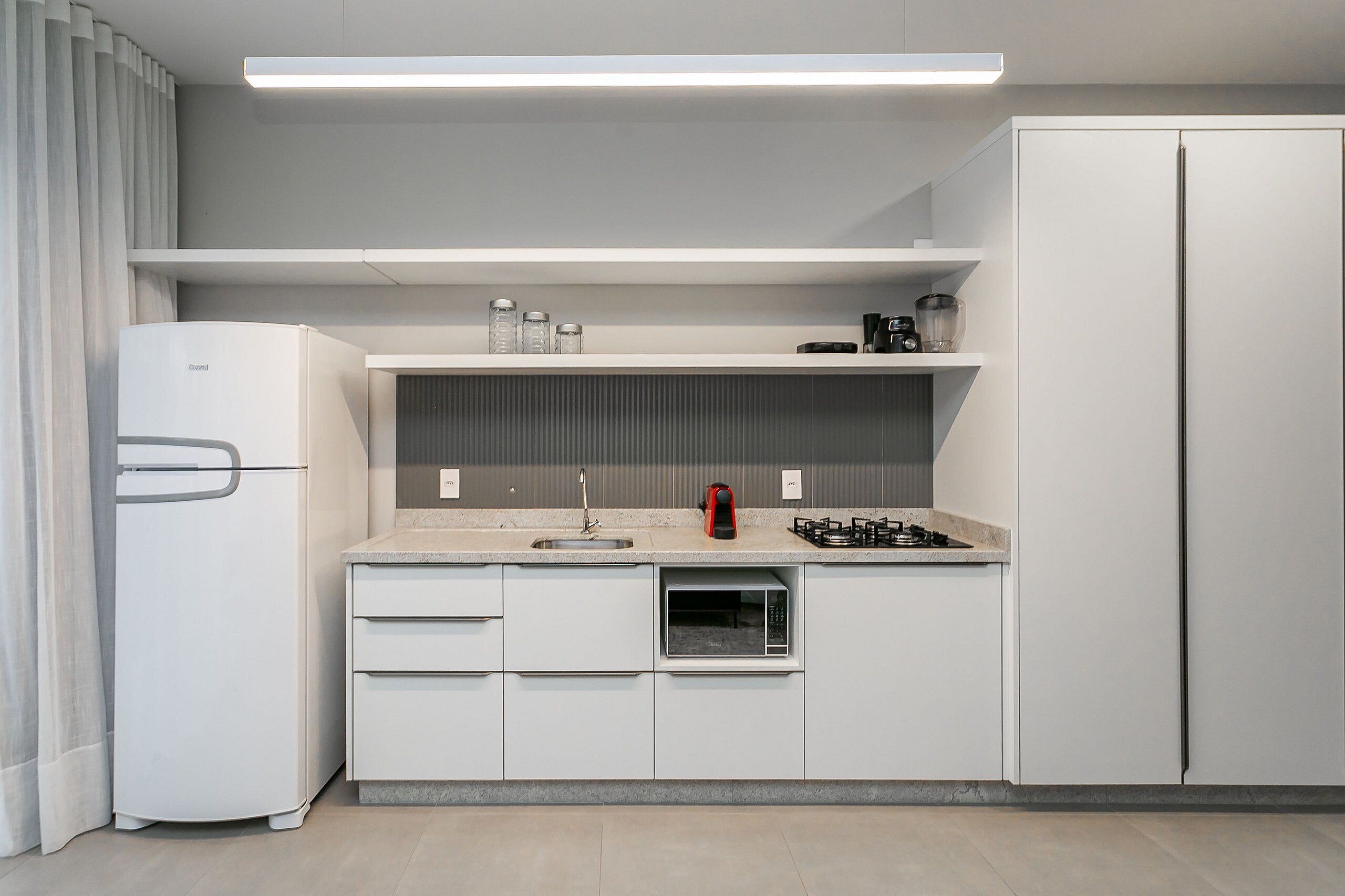 Eine moderne Küche mit weißen Schränken, einer eingebauten Mikrowelle, einem Gasherd und einem Kühlschrank.