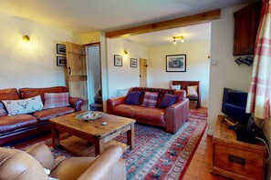 Una sala de estar acogedora con sofás de cuero, una mesa de centro de madera y un televisor.