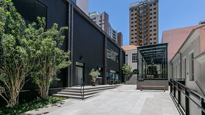 A modern building with a glass facade, a staircase leading to an upper level, and a bench in the foreground. - Pool with Sea View | WI-FI 200MB | Foodhall #TT5 (Florianópolis)