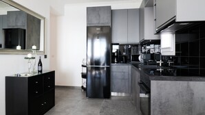 A modern kitchen with a large refrigerator, dark cabinetry, and a marble countertop. - Maison du Soleil by CorfuEscapes (Corfu)