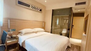 Ein Hotelzimmer mit Bett, Schreibtisch mit Stuhl, Telefon und einer Duschkabine.