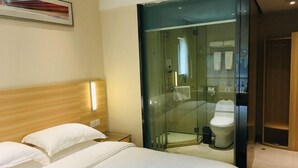 Ein Hotelzimmer mit einem Bett, einem Holzkopfteil, einer gläsernen Duschkabine und einem Holzkorpus.