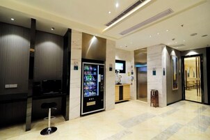 Un vestíbulo de hotel con una máquina expendedora, una recepción y una escalera.