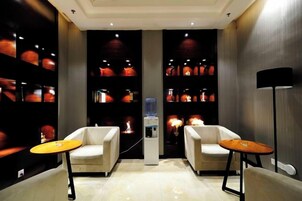 Una habitación de hotel con dos sillones, una mesita y un dispensador de agua.