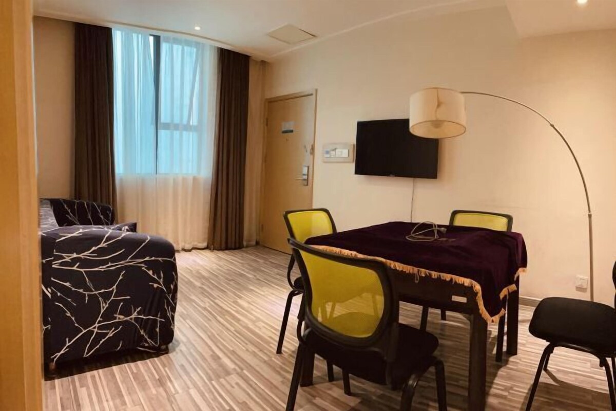 Ein Hotelzimmer mit einem Bett, einem Esstisch mit Stühlen, einem Fernseher und einer Lampe.