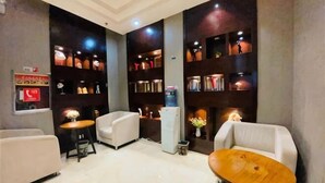 Eine Hotelhalle mit Sitzgelegenheiten, einer Rezeption und Bücherregalen.