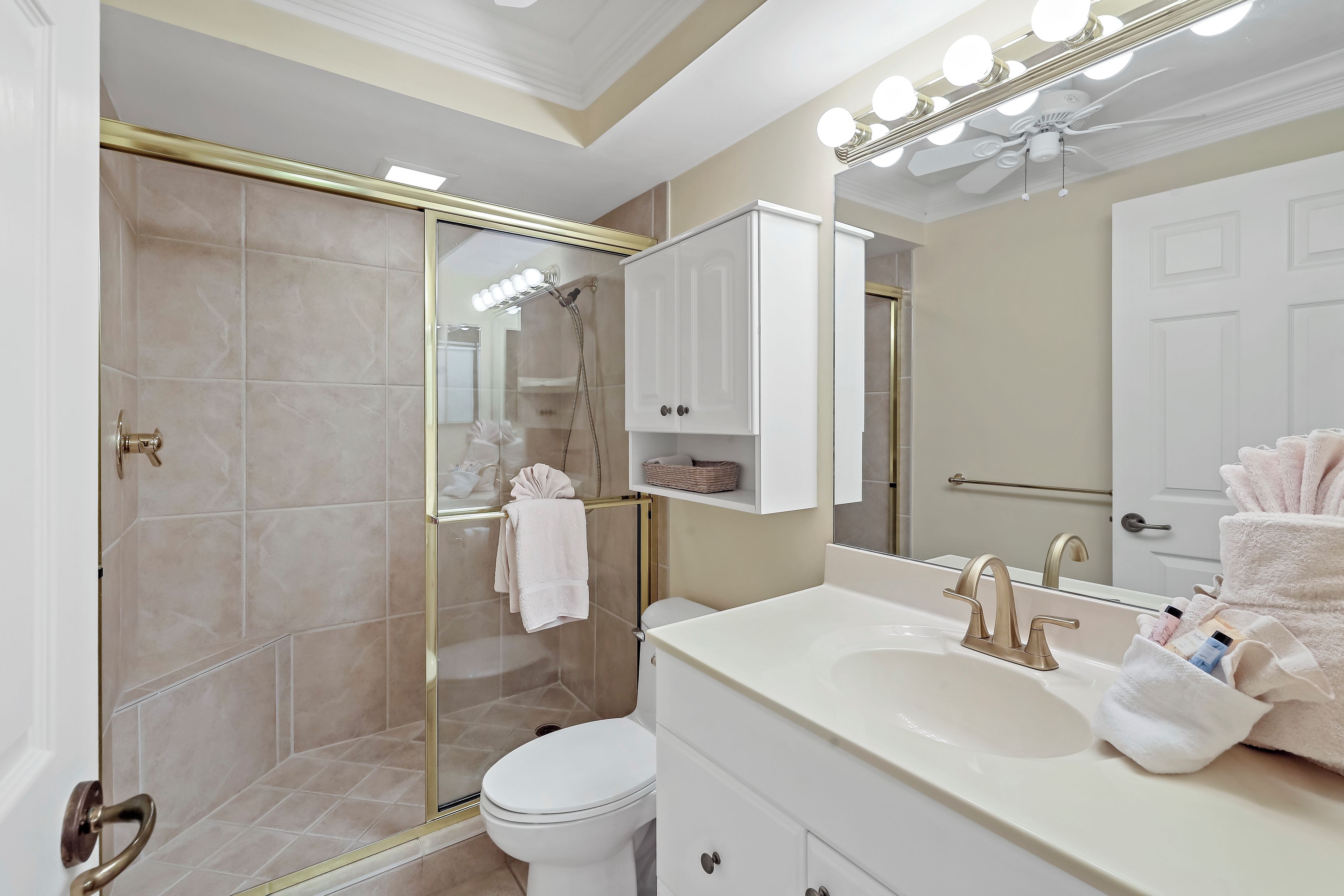Ein modernes Badezimmer mit begehbarer Dusche, Toilette, Waschbecken mit Unterschrank und einem großen, beleuchteten Spiegel.