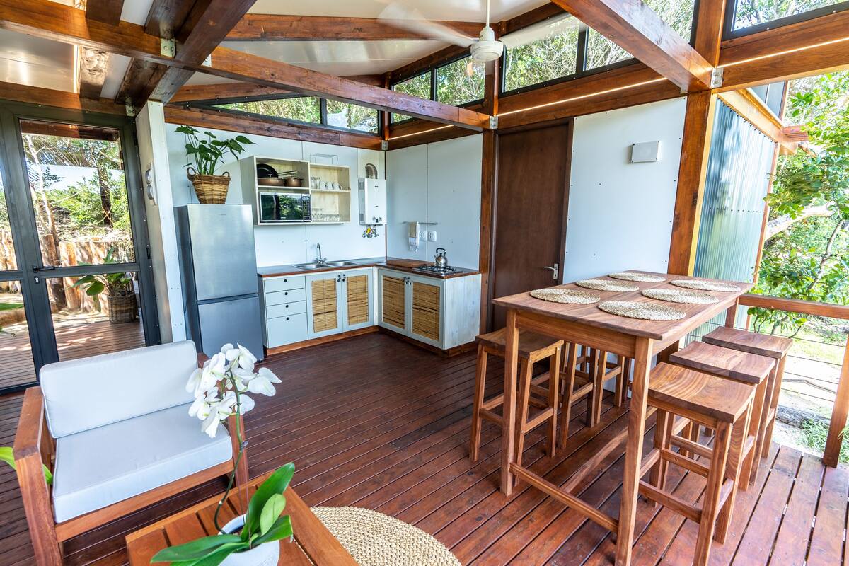 Eine Holzterrasse mit Essbereich, Küche und Sitzgelegenheiten.