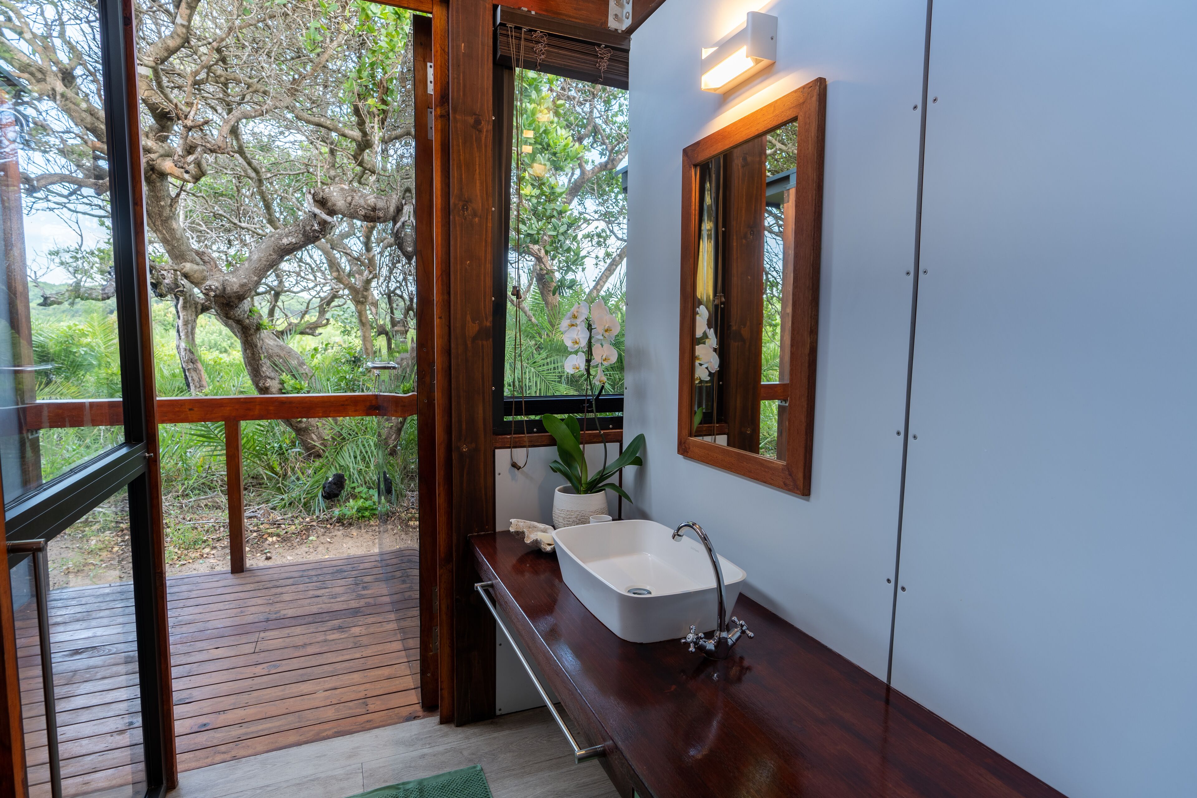 A bathroom with a wooden deck, a white sink, and a mirror.