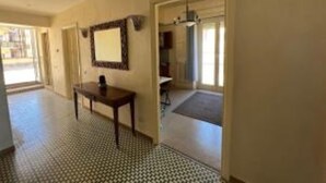 A hallway with a patterned floor, a table with a chair, and a mirror on the wall. - Forte Michelangelo apartment (Civitavecchia)