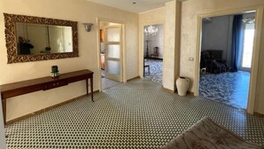 A hallway with patterned flooring, a mirror with an ornate frame, and a console table with a vase. - Forte Michelangelo apartment (Civitavecchia)