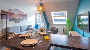 Un comedor moderno con una mesa alta para cuatro personas, un sofá y un gran ventanal con vistas.