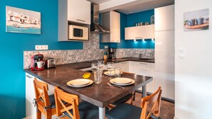 Una cocina moderna con una mesa de comedor lista para cuatro personas, equipada con una cafetera, copas de vino y un tostador.
