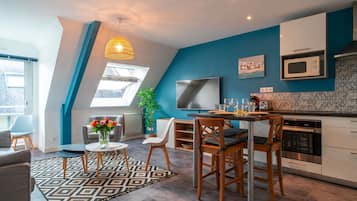 A modern kitchen with a dining area, featuring a large window, a microwave, and a dining table with chairs.