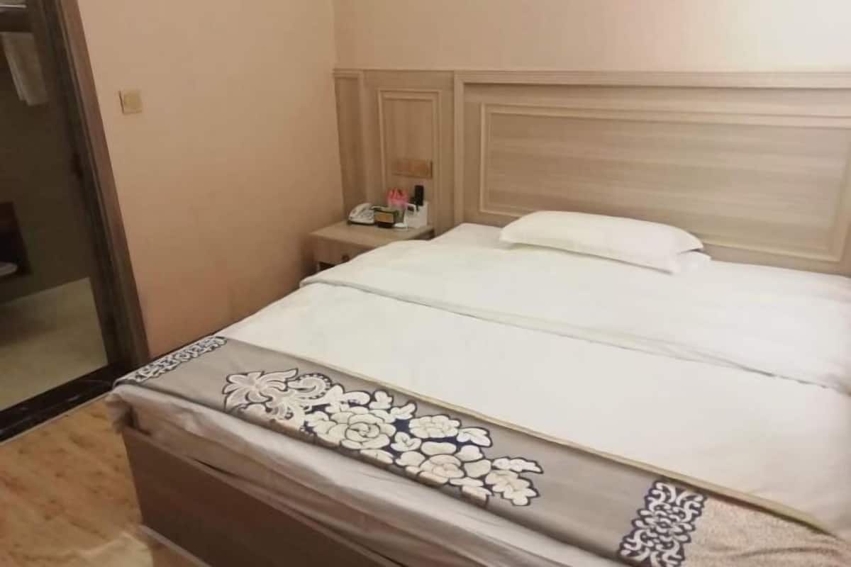A hotel room with a bed, a nightstand, and a mirror.
