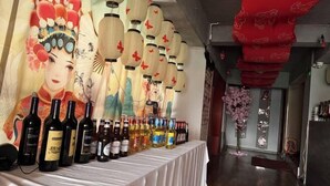 A table with various bottles of wine and a decorative wall with traditional artwork. - Chuxiong Haiheng Hotel (Chuxiong City)