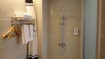 Un bagno con doccia, un porta asciugamani con asciugamani piegati e un water.