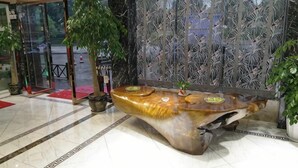 A reception area with a reception desk, a glass door entrance, and a decorative wall. - Chuxiong Haiheng Hotel (Chuxiong City)