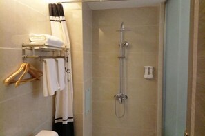 A bathroom with a shower, a towel rack with neatly folded towels, and a hanging towel. - Chuxiong Haiheng Hotel (Chuxiong City)