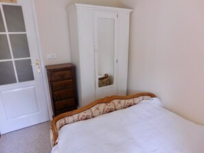 A bedroom with a bed, a dresser, and a wardrobe.