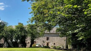 Ein Steinhaus mit einem Rasen und Bäumen.