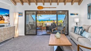 A living room with a sofa, a coffee table, and a view of the ocean through a sliding glass door. - Luxurious & Spacious Ocean Vistas (Wailea-Makena)