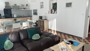 En moderne stue med en brun lædersofa, et sofabord og et spiseområde med bord og stole.