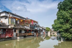 Un pintoresco pueblo acuático chino tradicional con edificios de varios pisos a lo largo de un canal, pasarelas de madera y faroles rojos.