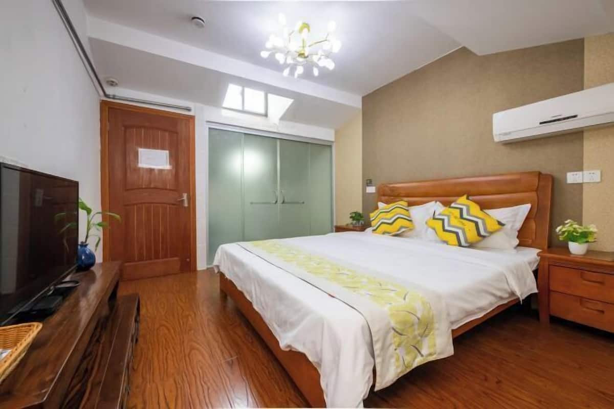 Un dormitorio con cama, piso de madera, televisor, armario y equipo de aire acondicionado.