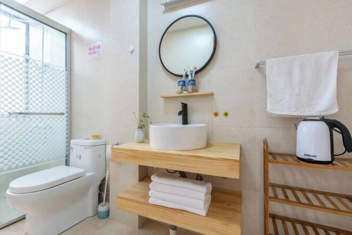Un baño moderno con inodoro, lavamanos, espejo y toallero.