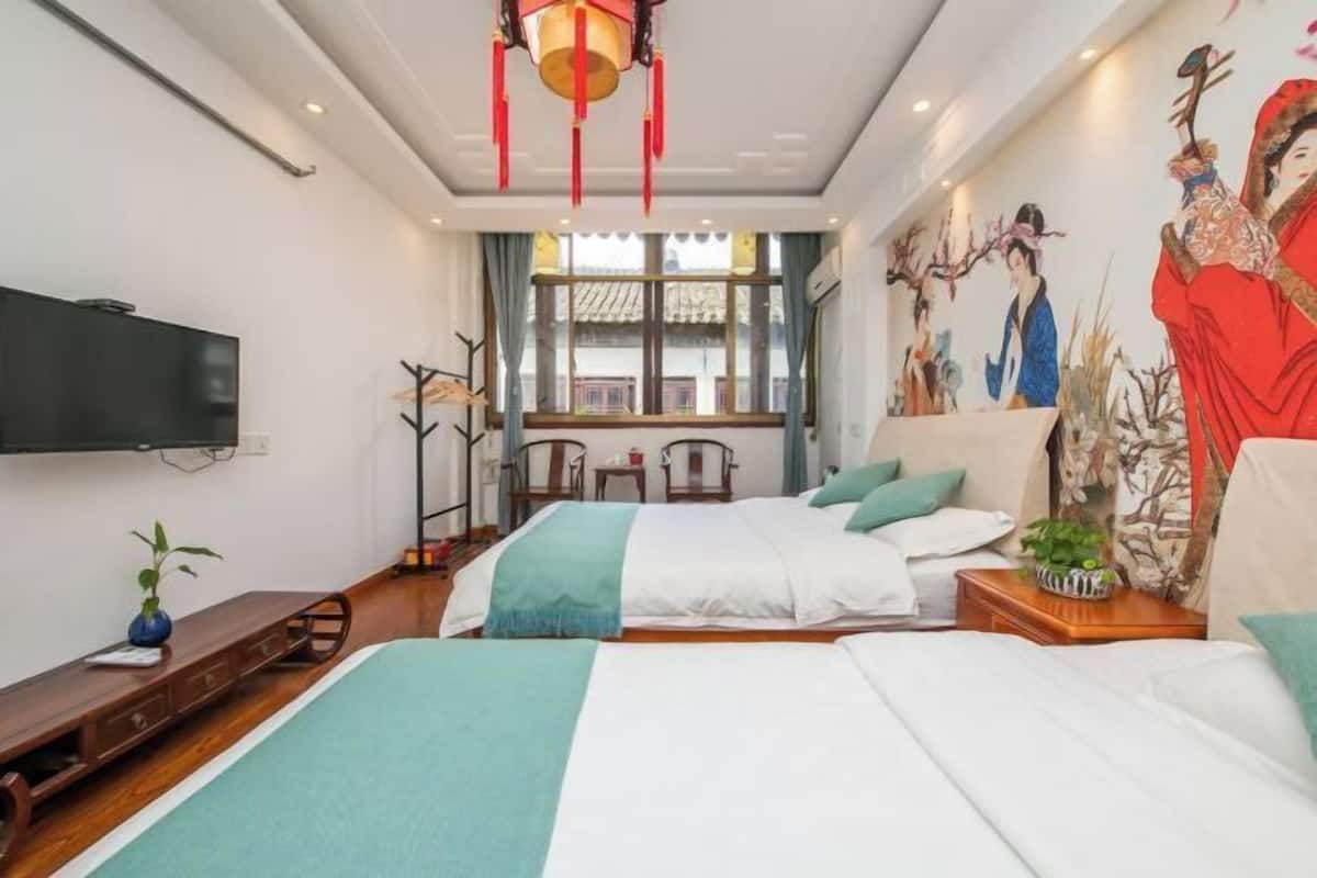 Una habitación de hotel moderna con dos camas, un televisor de pantalla plana, un ventanal con cortinas y un mural en la pared.