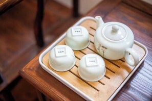 Un plateau avec une théière et trois tasses à thé, posé sur une table en bois.