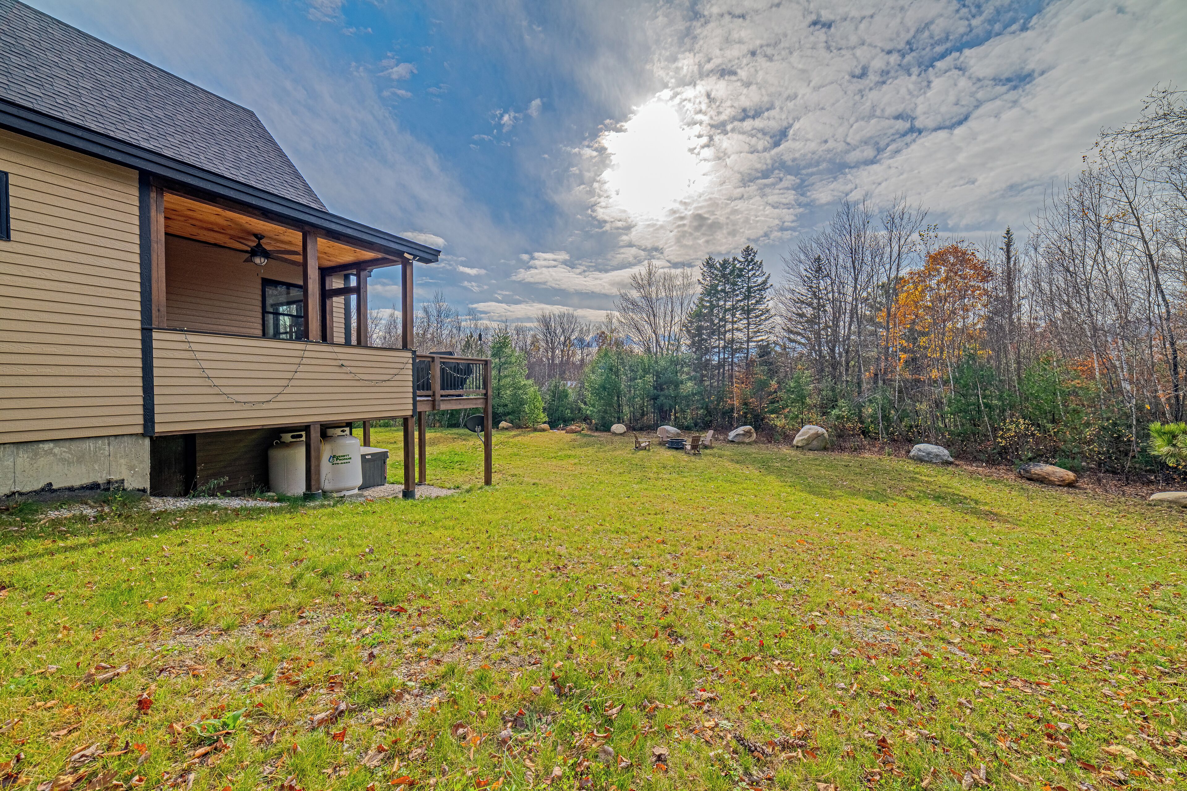Une maison moderne dotée d’un porche abrité, d’une pelouse et d’un paysage boisé en arrière-plan.