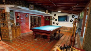 A billiards room with a pool table, a chess table, and a wall decorated with vinyl records. - Jardín de Silleteros Agro Parque Hotel (Envigado)