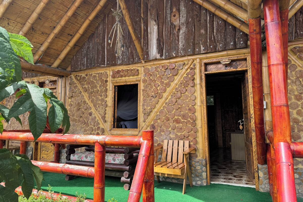 A rustic wooden building with a thatched roof, stone walls, and a wooden bench outside.