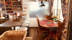 Una cocina acogedora con armarios de madera, una mesa de comedor con sillas y una silla de mimbre.