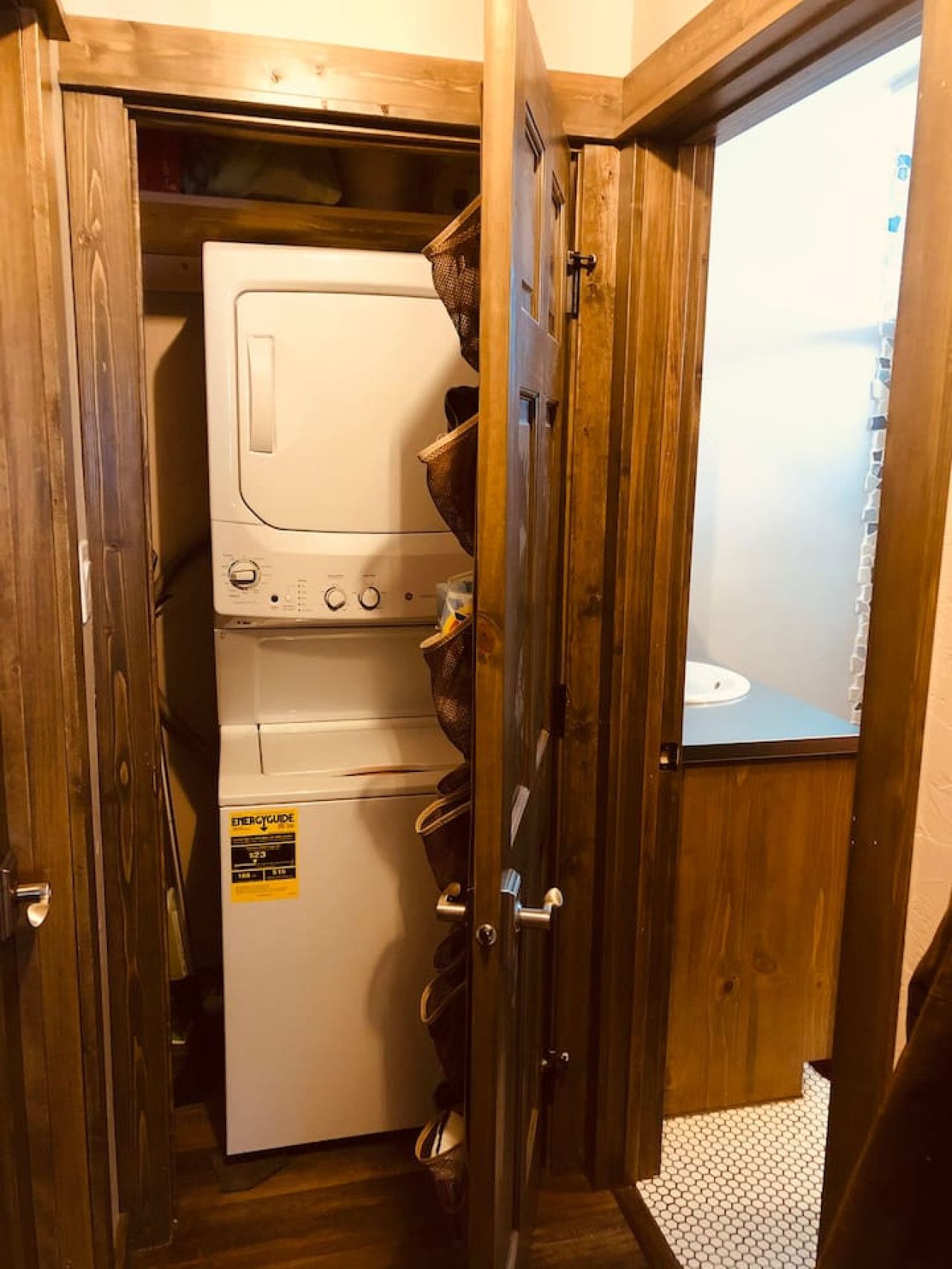 A laundry room with stacked washers and dryers, wooden doors, and a visible bathroom.