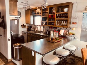 Une cuisine moderne dotée d’un îlot central, d’appareils électroménagers en acier inoxydable et de meubles de rangement en bois.