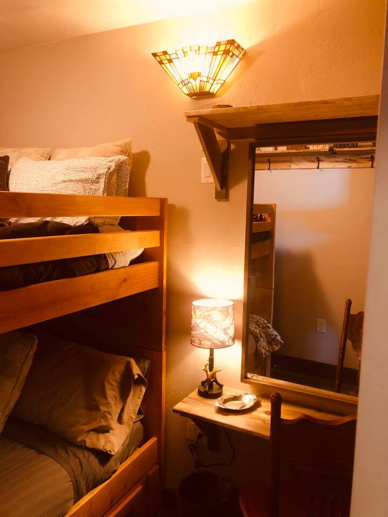 Ein Stockbett mit kleinem Schreibtisch und Spiegel.